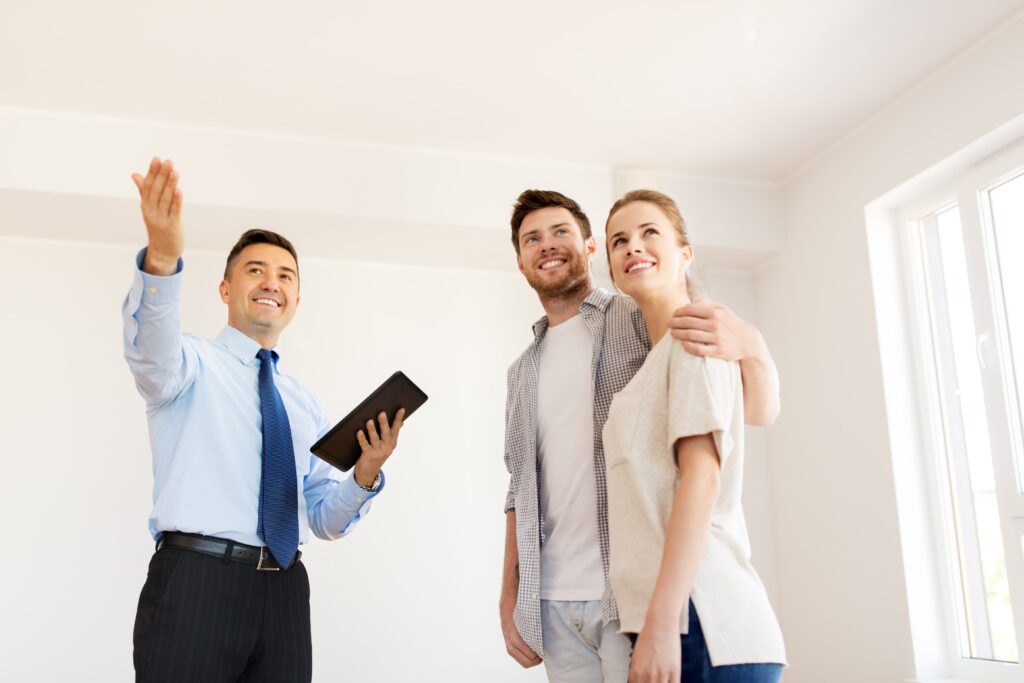 Ein Immobilienmakler zeigt einem glücklichen Paar eine neue Wohnung in Bad Nauheim. Der Makler hält ein Tablet in der Hand und erklärt die Details der Immobilie.
